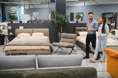 Female client discusses options with a male sales consultant during a shopping experience in a modern furniture store showroom