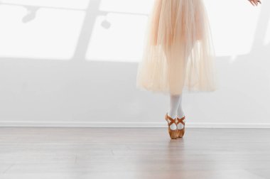 Bir dans stüdyosunda balerin, etek ve sivri ayakkabılar giyerek, zarafet ve disiplini somutlaştırarak ayak parmaklarının üzerinde zarif bir şekilde dengede duruyor.