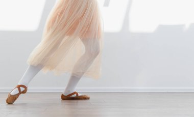 Balerin kız dans stüdyosunda bale çalışıyor, sivri ayakkabılar ve etek giyiyor, zarif bir dans gösterisi sergiliyor.