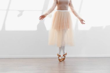 Dans stüdyosunda sivri uçlu ayakkabılar üzerinde duran balerin etek giyiyor ve zarif hareketlerini çalışıyor.