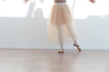 Genç balerin bir dans stüdyosunda bale yapıyor, etek ve sivri ayakkabılar giyiyor, zarafet ve adanmışlık sergiliyor.