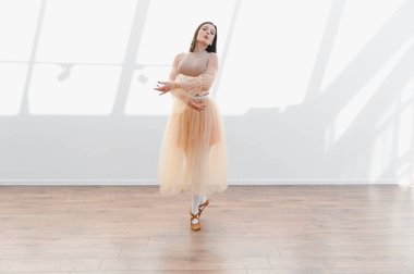 Balerin zarif bir şekilde dans eder parlak bir stüdyoda, hareketleri akıcı ve anlamlı, balenin güzelliğini ve kendini adamışlığını gösterir.