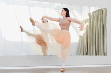 Zarif balerin, dans stüdyosunda aynanın önünde dans etmeye çalışıyor. Zarafetini ve kendini baleye adamış.