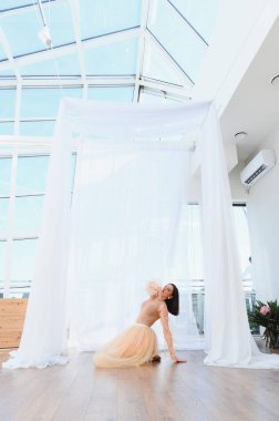 Dans kıyafetleri giyen genç bir kadın, parlak bir stüdyoda modern bir bale gösterisi yapıyor.