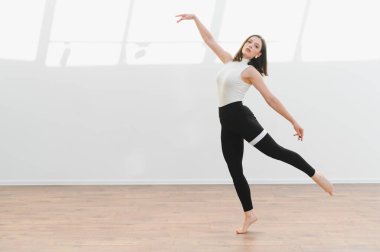 Parlak bir stüdyoda modern bir bale koreografisi uygulayan zarif bayan dansçı, dans için yeteneğini ve tutkusunu sergiliyor.