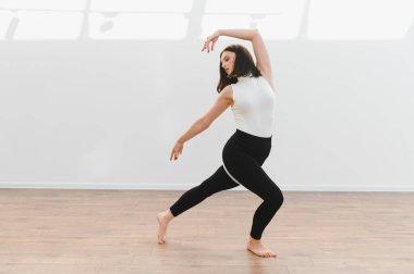 Dans öğrencisi ya da öğretmen ahşap zemini olan parlak bir stüdyoda modern dans koreografisi çalışıyor.