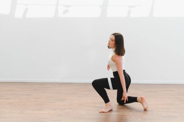 Dans öğrencisi, parlak bir stüdyoda modern koreografi uyguluyor. Parlak ahşap bir zemin ve bol miktarda doğal ışık var.