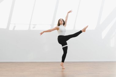 Güneşli bir stüdyoda modern bir bale gösterisi sergileyen zarif bir dansçı esneklik ve sanatsallık sergiliyor.