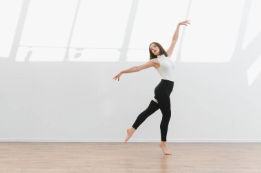 Zarif balerin, modern dans koreografisini parlak bir stüdyoda çalışıyor. Esneklik ve sanatsal ifade sergiliyor.