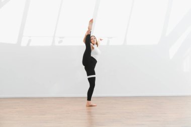 Modern dans koreografisini parlak bir stüdyoda uygulayan esnek bayan dansçı zarafet ve atletizm sergiliyor.