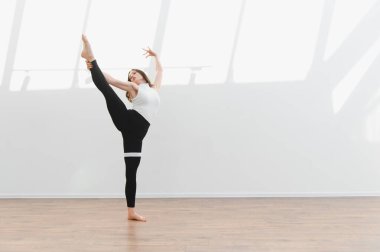 Modern koreografiyi pratik yapan dans hocası doğal ışık, zarafet ve hareket yeteneğiyle dolu parlak bir stüdyoda.