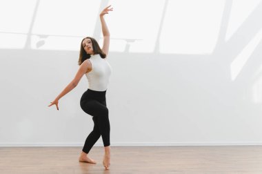 Parlak bir stüdyoda zarif hareketler sergileyen zarif dansçı, çağdaş dans yoluyla esneklik ve sanatsal ifade sergiliyor.