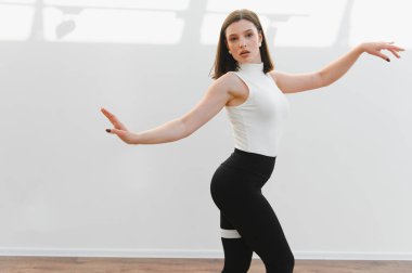 Parlak bir stüdyoda dans figürleri yapan zarif dansçı yeteneğini ve hareket tutkusunu sergiliyor.