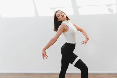 Parlak bir stüdyoda modern bir dans gösterisi sergileyen zarif dansçı yeteneğini ve hareket tutkusunu sergiliyor.