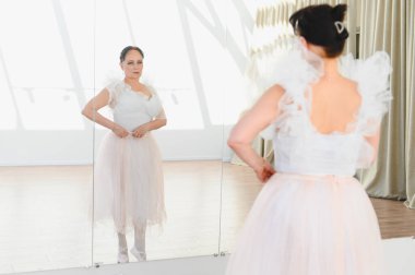 Yaşlı balerin dans stüdyosunun içindeki bir aynanın karşısında eteğini kontrol ediyor ve gösterisine hazırlanıyor.