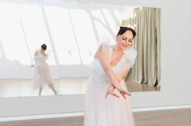 Yaşlı balerin bir dans stüdyosunda bale hareketleri yapıyor, yaşlılıkta dans için zarafet ve tutku gösteriyor.