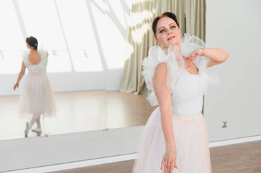 Beyaz etekli yaşlı balerin bir dans stüdyosunda ayna ile dans ediyor. Zarafet ve bale tutkusu sergiliyor.