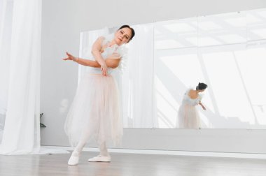 Yaşlı balerin, parlak bir stüdyoda zarif bir şekilde dans eder. Yansıması, tutkusunu ve baleye olan bağlılığını yansıtır.