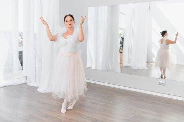 Yaşlı balerin, dans stüdyosunda ayna eşliğinde bale egzersizleri yapıyor. Tutkusunu ve dans etmeye olan bağlılığını sergiliyor.