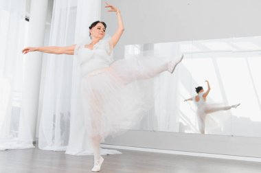 Zarif üst düzey balerin, parlak bir stüdyoda bale hareketleri yapıyor. Zarafet ve kendini dansa adamış.