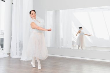 Yaşlı balerin, parlak bir stüdyoda zarif bir şekilde dans eder. Tutkusunu ve kendini baleye adadığını gösterir.