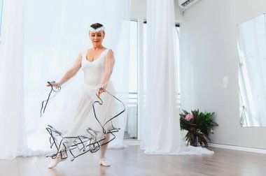 Kıdemli balerin, parlak bir stüdyoda zarif bir şekilde dans ediyor. Yaşlandıkça baleye olan tutkusunu ve zarafetini gösteriyor.