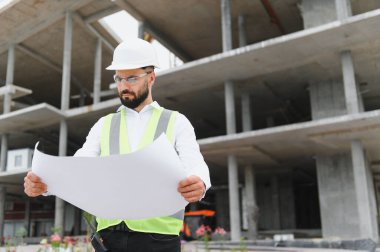 İnşaat planlarını inceleyen, inşaat sürecini güvence altına alan ve yeni geliştirme projesini denetleyen mühendis