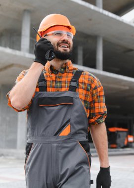 İnşaat işçisi, inşaat alanında iletişim kurmak için bir telsiz kullanıyor.