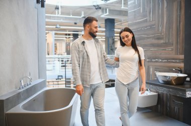 Genç çift yeni banyo ekipmanları arıyor, modern banyo küvetleri ve ev dekorasyonu için lavabo tasarımları seçiyorlar.