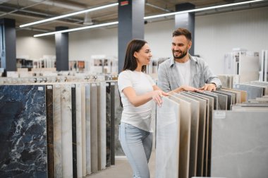 Zemin malzemesi almak için alışveriş yapan mutlu bir çift. Fayansçı dükkanından numune seçiyorlar. Ev geliştirme ve iç tasarım planlama