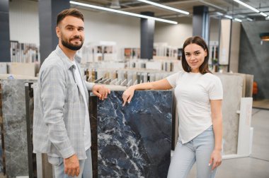 Erkek ve kadın büyük formatlı mermer fayanslar seçiyor, bir hırdavatçıda iç dekorasyon projesi planlıyorlar.