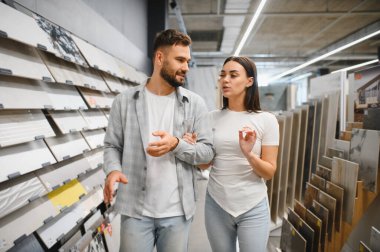 Bir hırdavatçıda seramik fayanslar seçen genç bir çift ev geliştirme seçeneklerini tartışıyor.