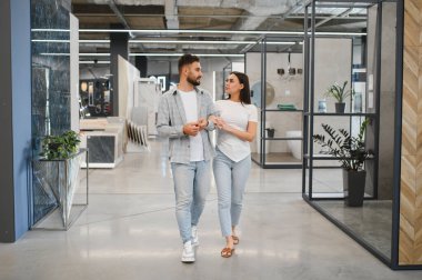 Yeni fayanslar ve banyo kavramları için sergi salonunu keşfeden genç çift, birlikte ev geliştirme projesi planlıyorlar.