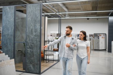 Genç bir çift hırdavatçı dükkanında döşeme ve duvar döşemesi alışverişi yapıyor ve evlerinin yenilenmesi için malzeme seçiyor.