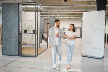 Yeni fayanslar ve döşemeler arayan genç bir çift, bir sergi salonunda yürüyorlar, iç tasarım planlıyorlar.