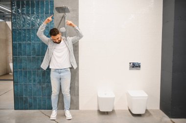 Galeride bir adam yeni bir duş ve tuvalet kurulumunu hayal ediyor, ev yenilemesini planlıyor, modern stilleri karşılaştırıyor.