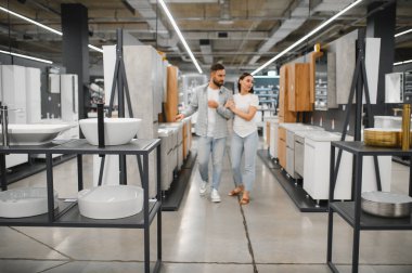 Yeni banyo lavabolarını ve dolaplarını seçen bir çift, bir perakende galerisinde ev yenileme fikirleri arıyorlar.