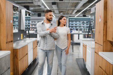 Çift, modern ev dekorasyonu için yeni banyo tesisatı seçiyor, iç tasarım planlıyor.