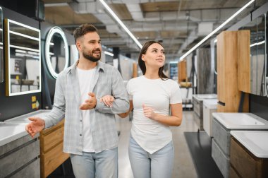 Modern banyo mobilyalarını ve lavaboları seçen genç bir çift, bir sergi salonunda birlikte yenileme yapmayı planlıyorlar.