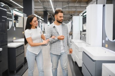 Genç çift farklı banyo dolaplarını ve lavaboları keşfederek yeni bir tasarım üzerinde karar veriyorlar.