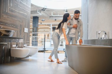 Genç çift banyoda yeni bir küvete dokunuyor, iç tasarım ve yenileme planlıyorlar.