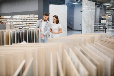 Ev yenileme projesi için seramik döşeme seçen genç çift. Meşgul bir sergi salonunda alışveriş yapmak.