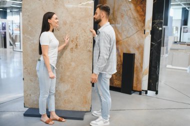 Bir çift, ev geliştirme galerisinde mermer bir levha seçiyor. Evlerini yenilemeyi ve geliştirmeyi planlıyorlar.