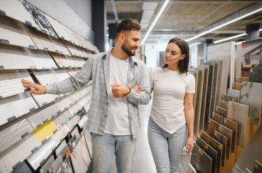 Genç çift yeni seramik fayanslar seçiyor. Daire geliştirmek için. Ev içi tasarım projesi için malzeme seçiliyor