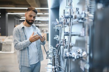 Sakallı adam, banyo eşyaları ve su tasarrufu seçenekleri ararken bir hırdavatçı koridorunda modern duş başlıklarını karşılaştırıyor.