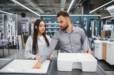 Satış elemanı, modern bir hırdavatçıda yeni bir banyo seçmesi için kadın müşteriye yardım ediyor.