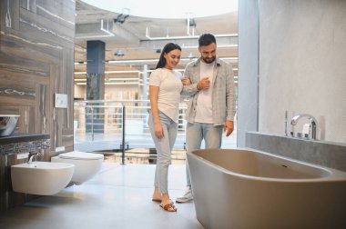 Genç çift, hırdavatçıda yenileme ve iç tasarım için modern küvet ve banyo ekipmanlarını seçiyor.