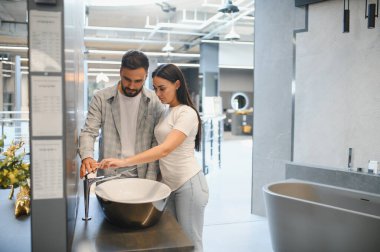 Genç çift yeni banyo tasarımları ve ev dekorasyonu için modern lavabo ve musluk seçiyorlar.