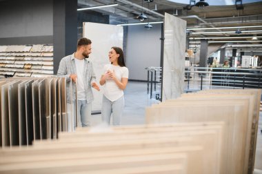 Çift yeni döşeme fayansları alıyor, evleri için yenileme planlarını tartışıyorlar. Şaşırtıcı ya da heyecanlı bir kadın.