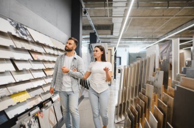 İnşaat malzemeleri almak için alışveriş yapan genç bir çift, hırdavatçıda yeni döşeme ve duvar döşemeleri seçiyorlar.